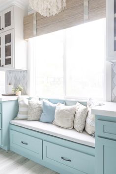 a kitchen with blue cabinets and white counter tops is pictured in this image, there are pillows on the window sill