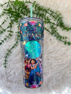 the disney princess tumbler has been decorated with images and is next to a plant