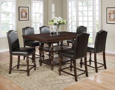 a dining room table with chairs and a vase filled with flowers on top of it