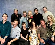 a group of people sitting next to each other in front of a blue wall and smiling