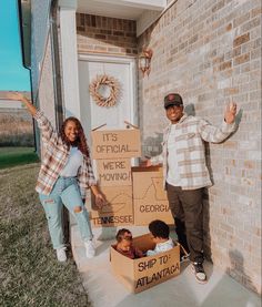 a man and woman standing next to cardboard boxes on the front steps of a house