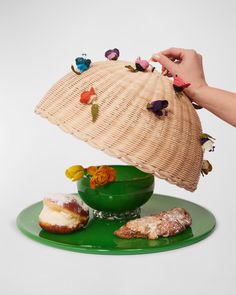 a person holding a basket over a plate with pastries on it and flowers in the bowl