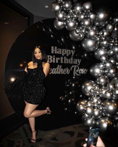 a woman standing in front of a black and silver balloon arch with the words happy birthday leather rowe on it