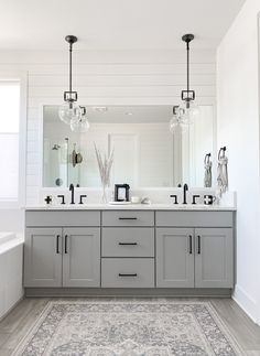 a large bathroom with two sinks, mirrors and lights on the wall above it is shown