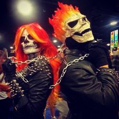 two people dressed up in costumes with chains and skulls on their faces, one wearing a skull mask