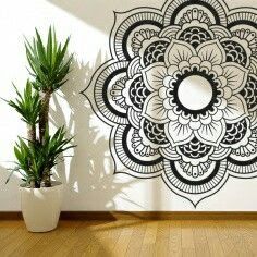 a potted plant sitting next to a wall with an intricate flower design on it