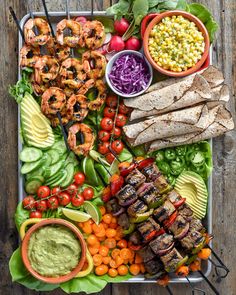 a platter filled with meat, veggies, and other foods on skewers