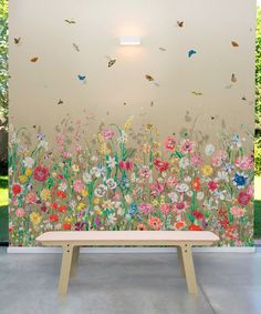 a bench sitting in front of a wall with flowers and butterflies on it