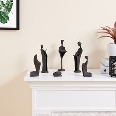 three black sculptures sitting on top of a white table next to a potted plant