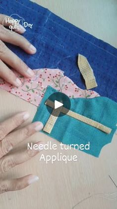 two hands are working on an applique that is being made from fabric and material