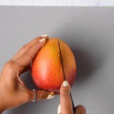 a woman is holding a piece of fruit in her left hand and pointing to it