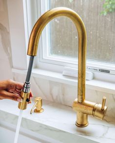 a person is washing their hands under a faucet in the kitchen sink with water running from it