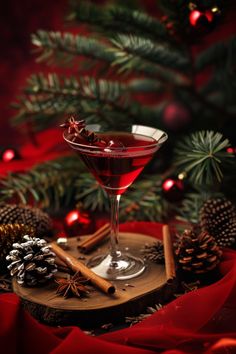 a glass filled with red liquid next to christmas decorations