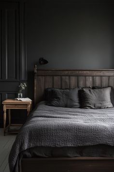 a bed sitting in a bedroom next to a wooden table and lamp on top of it