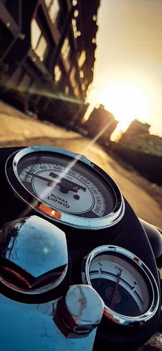 the gauges are on top of the motorcycle's handlebars as the sun sets in the background