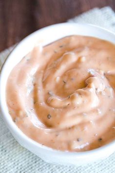 a white bowl filled with sauce sitting on top of a table next to a napkin