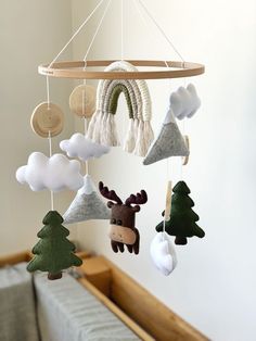 a crib mobile with deer and trees hanging from it