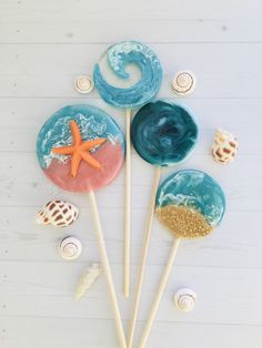 three lollipops with sea shells and starfish on them sitting on a white surface