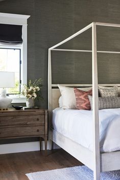 a white bed sitting in a bedroom next to a window