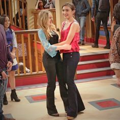 two young women standing next to each other in front of a crowd on the set of friends like us