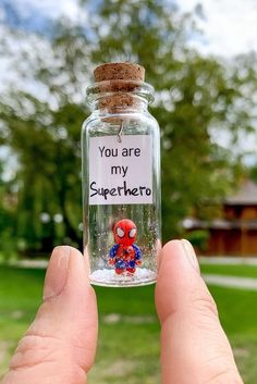 someone holding up a glass bottle with a spiderman message on the top and bottom