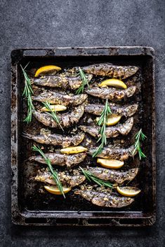 grilled fish with lemons and rosemary on a baking sheet