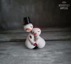 two snowmen are hugging each other on the cement floor in front of a wall