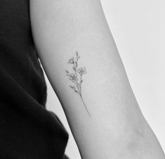 a small flower tattoo on the left inner arm and shoulder is shown in black and white