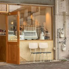 two white chairs sitting in front of a coffee shop