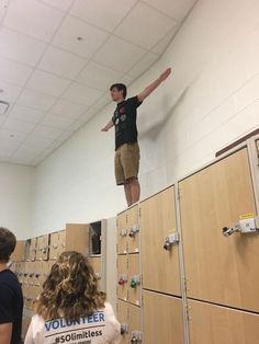 a man standing on top of a stack of lockers in a room filled with people