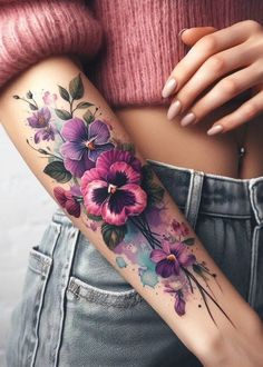 a woman's arm with purple flowers on it and green leaves in the middle