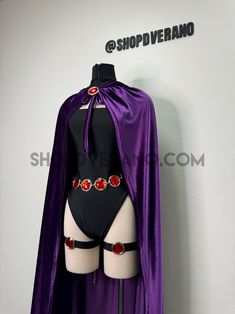 a mannequin wearing a purple cape and black bodysuit with red jewels on it