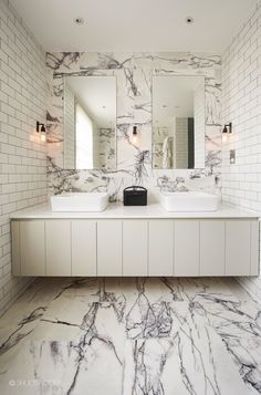 a bathroom with two sinks and mirrors on the wall next to each other in white marble