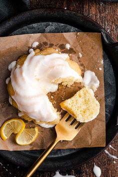 a piece of cake with icing and lemons on a plate next to a fork