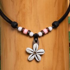 This shell necklace with a beautiful flower pendant is handmade by us. The pendant made of 5 real cowrie shells has a diameter of approx. 30 - 40 mm. We use extra sturdy cowhide leather, which is particularly tear-resistant. Our leather is exclusively produced in Germany and is vegetable tanned, i.e. without chemicals. This protects the wearer's health and our environment. The chain can be variably adjusted using two wooden beads (left and right in the picture) and therefore fits any neck size. Handmade Adjustable Flower Necklace For Beach, Handmade Flower Pendant Necklace For Beach, Adjustable Flower Pendant Necklace For Beach, White Flower Charm Necklace For The Beach, White Flower Charm Necklace For Beach, Bohemian White Flower Necklace For Beach, Wood Beads Jewelry, Girl Surfer, Mens Leather Necklace