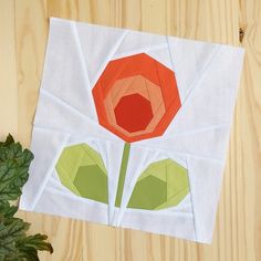 an origami flower on top of a piece of paper next to a potted plant