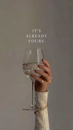 a woman holding a wine glass with the words it's already yours