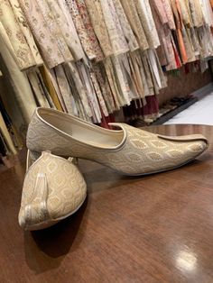 a pair of white shoes sitting on top of a wooden table in front of dresses