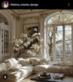 a living room filled with white furniture and large windows overlooking the trees in front of it