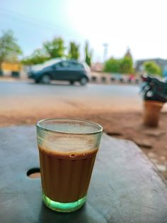 a cup of coffee sitting on top of a wooden table next to a parking lot