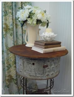 a vase with flowers and books on top of an old table in front of a window