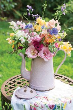 a vase filled with flowers sitting on top of a wooden table in the middle of a field