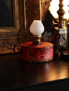 an old fashioned lamp sitting on top of a wooden table next to a painting and other antique items