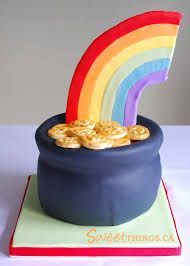 a cake shaped like a pot with cookies in it and a rainbow decoration on top