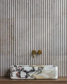 a marble sink sitting on top of a wooden counter next to a wall mounted faucet