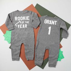 two baby onesuits with the words rookie of the year printed on them