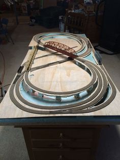 a wooden table topped with a model train set on top of plywood planks