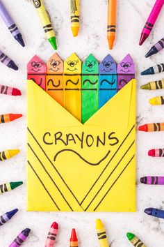 an envelope with crayons written on it surrounded by colored crayons