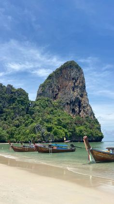 two boats sitting on top of a sandy beach next to an island in the ocean