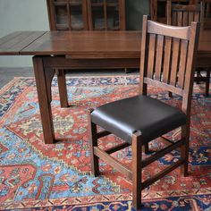 a wooden table and chair sitting on top of a rug